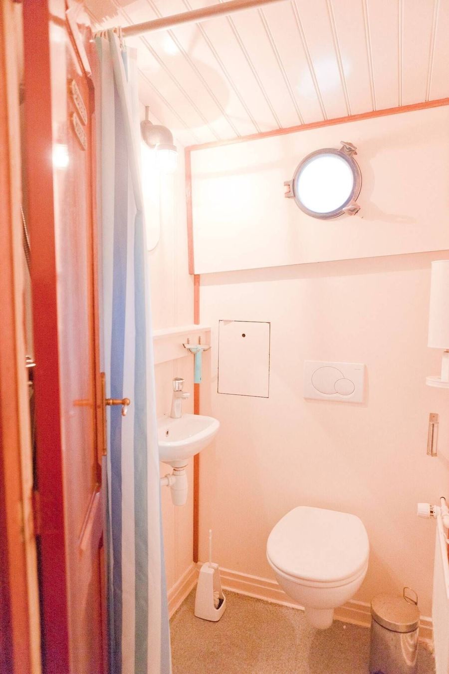 A bright shower room with a porthole, wash basin and toilet