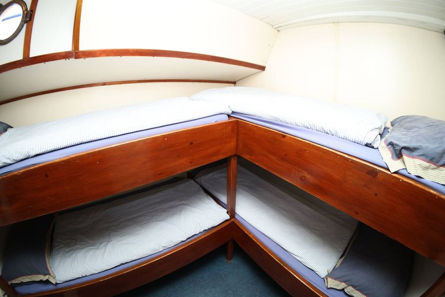 Four-person cabin with wooden bunk beds and fresh white bedding