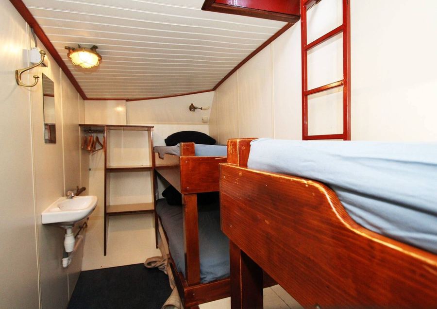A cabin with wooden bunks, a wash basin and a small ladder