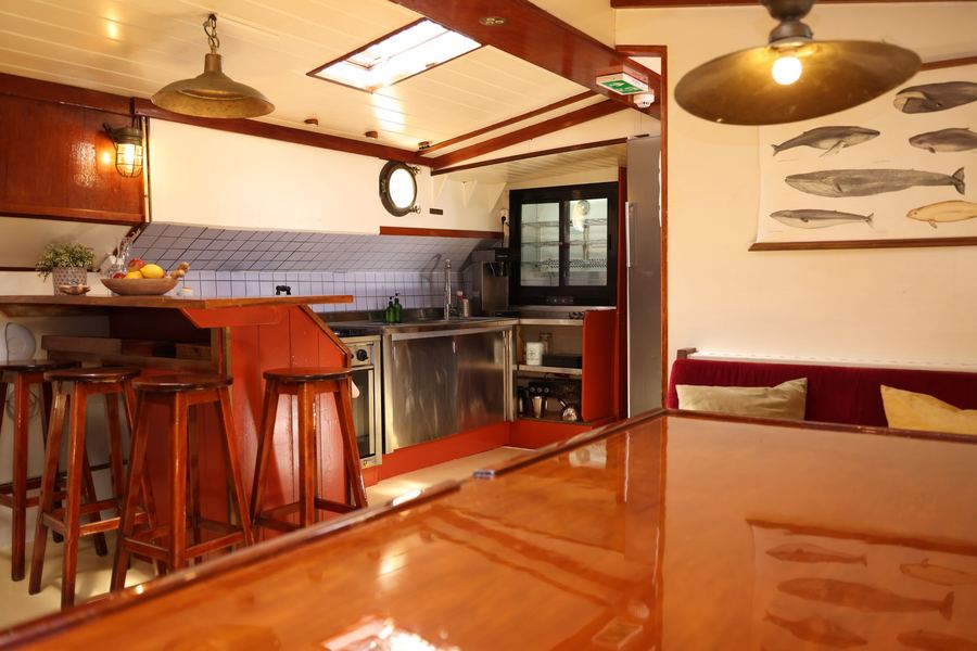 Bar stools at the varnished counter in front of the open kitchen