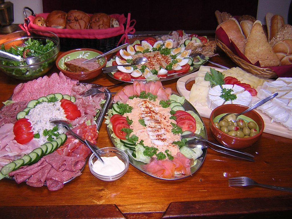 Platters of cold cuts, eggs, cheese and bread laid out on the wooden table